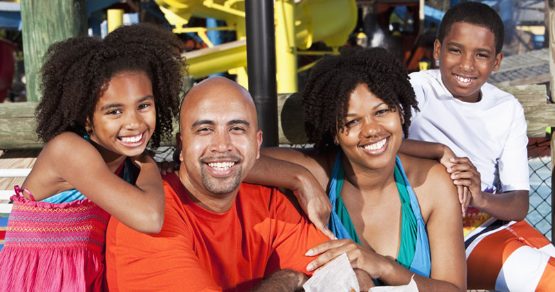 Happy black family of four posing for a photo outside a restaurant